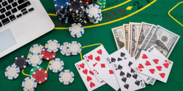 poker chips with banknotes placed on a laptop keyboard. Poker concept