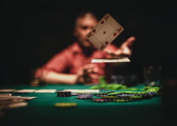 One mature man playing poker late by night, throwing playing cards on table.