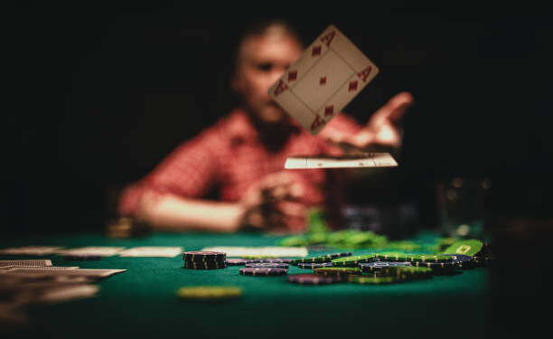 One mature man playing poker late by night, throwing playing cards on table.