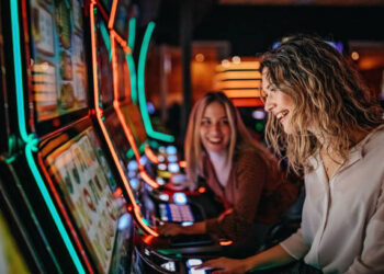 Girl friends gambling in casino on slot machinery