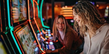 Girl friends gambling in casino on slot machinery