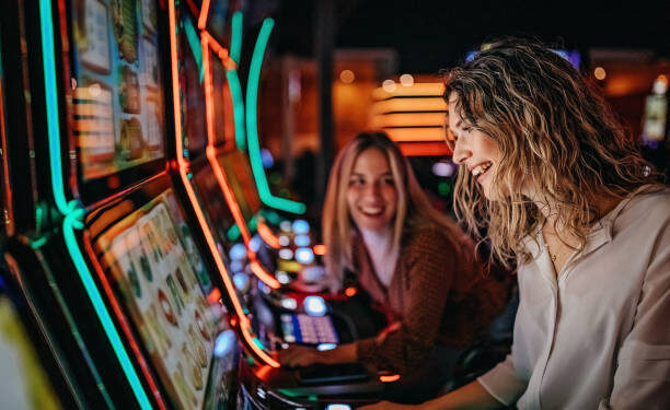 Girl friends gambling in casino on slot machinery