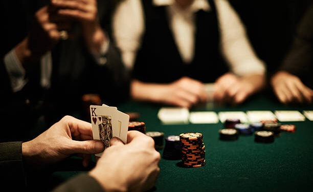 Hands of card player holding king of hearts