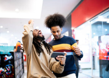 Brothers watching sports or playing on the smartphone at the mall